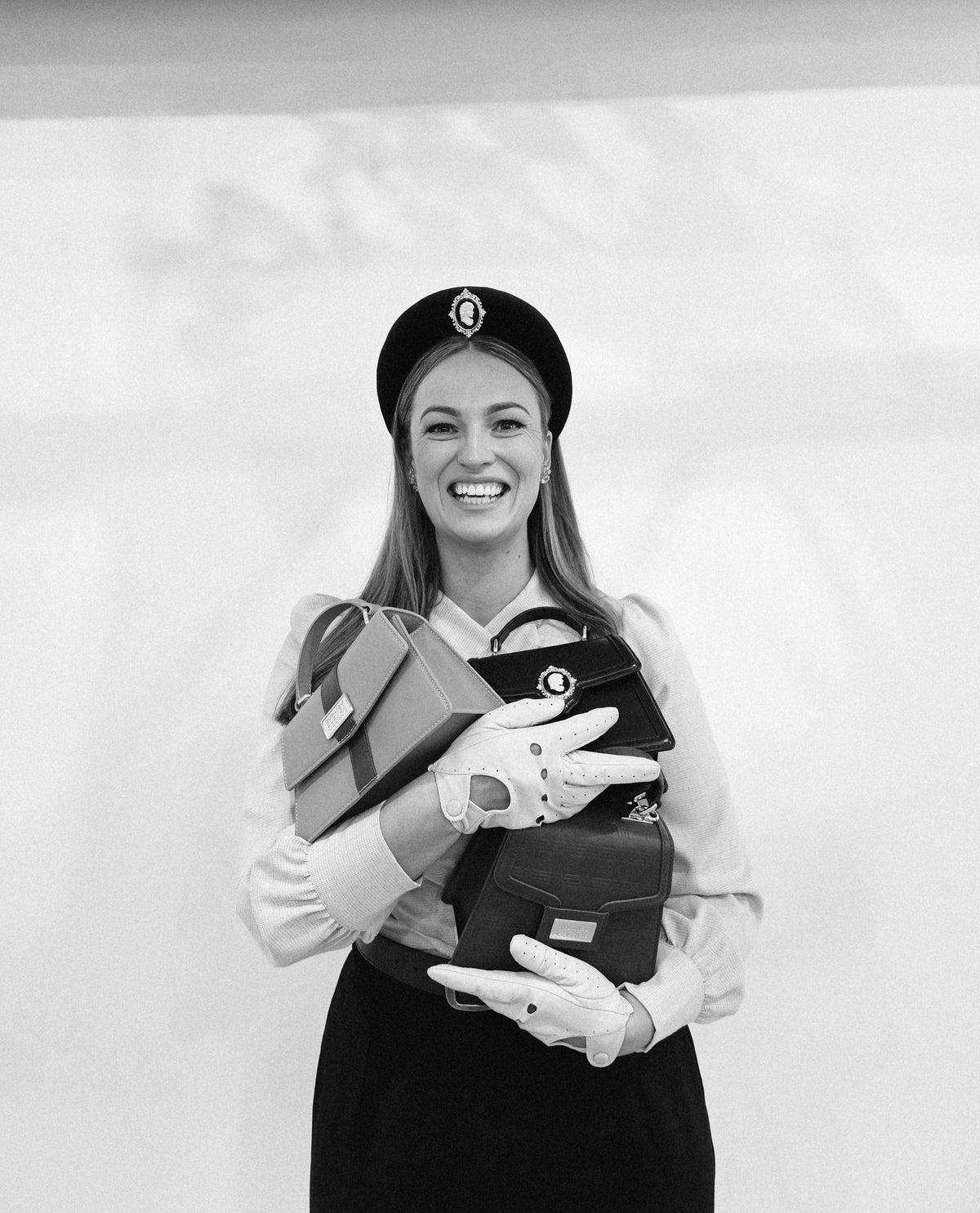 Katie, founder of Sydney George, holding three handbags